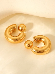 Detailed close-up of golden C-shaped ball earrings with a high-shine polished mirror finish