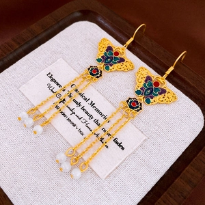 Detail of vintage butterfly earrings with colorful enamel, tassels, and white beads