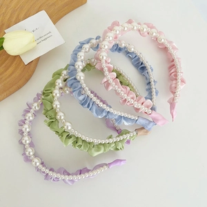 Close-up of pearl mesh headbands in purple, green, blue and pink on a wooden tray