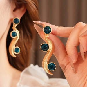 Detailed close-up of vintage gold S-shaped earrings featuring three blue rhinestones