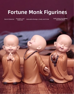 Macro shot of three brown resin monk figurines with matte finish and dark prayer beads