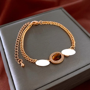 Detail of gold-plated bracelet with oval tiger eye stone and cubic zirconia inlay