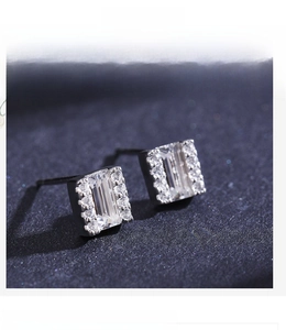 Macro detail of silver square stud earrings with central cubic zirconia and halo accents