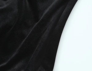 Close-up of the premium black velvet fabric texture with soft light reflections on bodysuit