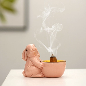 Pink ceramic bunny incense burner with smoking cone in a modern European home decor style
