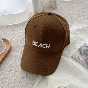 Detailed embroidery of white BEACH letters on a coffee-colored cotton baseball cap