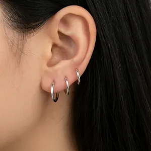 Detailed view of silver hoop earrings in sizes 9mm to 15mm on model ear cartilage
