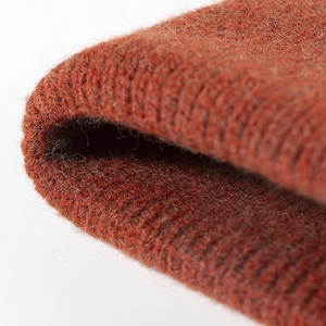 Close-up of orange-brown chunky knit winter beanie showing thick wool fiber textures