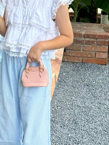 Mini-Umhängetasche für Mädchen aus rosa PU-Leder in der Hand im Freien