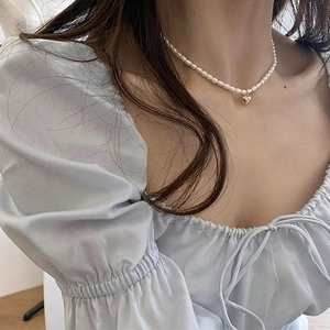 Elegant natural freshwater pearl necklace with a golden heart pendant worn on the neck