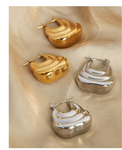 Macro shot of gold and silver textured wave earrings on elegant satin fabric
