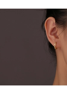 Detailed view of model wearing a gold hollow heart-shaped huggie earring