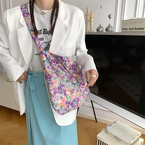 Detail view of purple floral canvas bag styled with a white blazer and blue dress