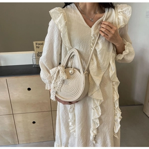 Detail of cream woven straw bag featuring elegant pearl accents and a lace bow charm