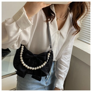 Detail of black lace shoulder bag with large satin bow and white pearl handle ornament