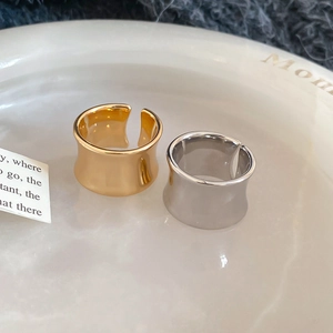 Minimalist wide open-style rings in gold and silver finish on a white ceramic tray