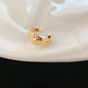 Macro view of gold layered textured open ring on elegant white silk fabric