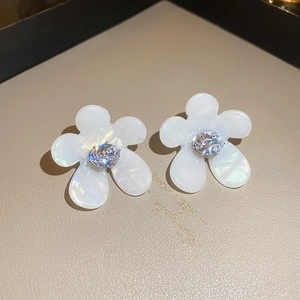 Detail of floral pearl earrings featuring a large oval zircon center on a leather base