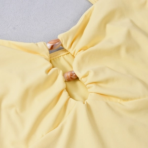 Detail of yellow knit top featuring decorative brown marble buttons on the neckline