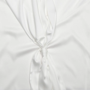 Gros plan sur la texture du tissu en soie blanche et le détail du nœud de la robe de soirée