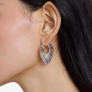 Detail of silver fan-shaped heart earrings on model showing sunburst metal texture