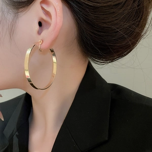 Polished large gold hoop earrings on model highlighting minimalist metallic texture