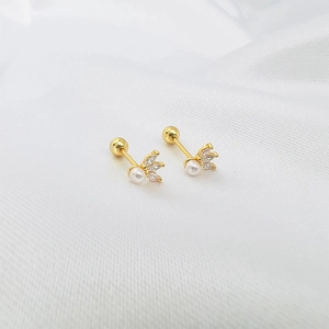Detail of gold pearl earrings with zircon leaves and screw back on white silk