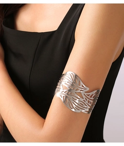 Macro detail of silver-finish cutout leaf pattern arm cuff on model's upper arm