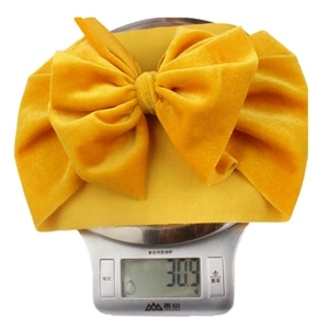 Detailed shot of yellow velvet baby bow headband on a scale weighing 30.9g