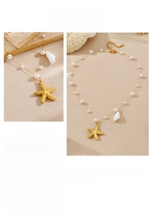 Détail du collier pendentif étoile de mer doré avec perles et breloque coquillage sur sable