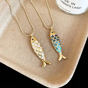 Artistic gold ball chain necklace featuring blue and white enamel fish shaped pendants