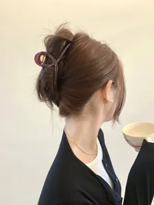 Detailed view of a large 13cm dark red hair claw clip worn in an elegant updo hairstyle