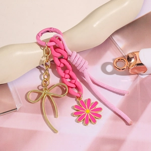 Détail du porte-clés chaîne rose avec pendentif nœud doré et breloque marguerite