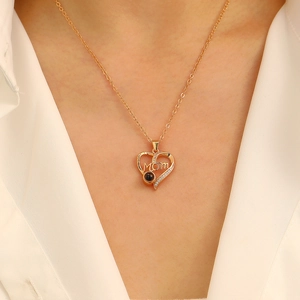 Detail of gold heart pendant with MOM engraving and crystals worn on a model