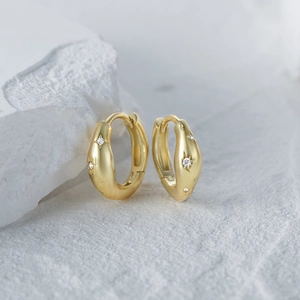 Detail of gold huggie hoop earrings with starburst engraving and micro zircon inlay