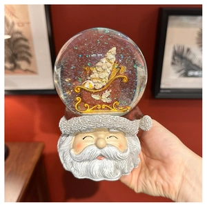 Detail of vintage Christmas snow globe featuring intricate Santa base and golden sleigh