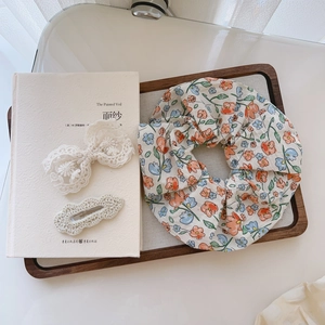Floral scrunchie set with white lace bow clip and knit hair pin on a wooden tray