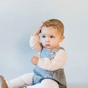 Infant nylon soft headband with brown hollow bow on a clean pastel background
