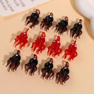 Detailed view of handmade glass octopus charms in red and black for DIY jewelry crafts