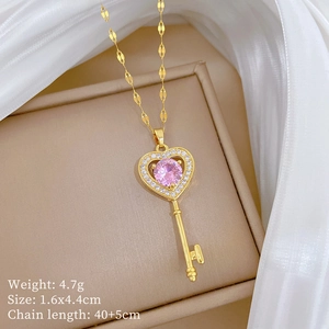 Detailed view of a gold heart key pendant necklace with a pink crystal and cubic zirconia