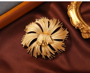 Macro shot of vintage gold floral brooch with radial metallic leaf details on silk