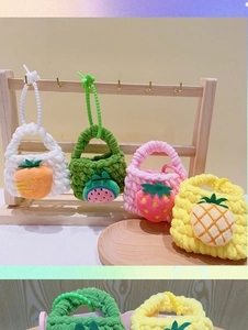 Close-up of handmade crochet fruit coin purses hanging on a wooden display stand