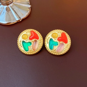 Detailed view of vintage gold stud earrings with colorful enamel patterns and bead edges