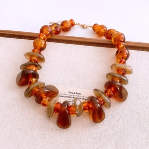 Detail of amber acrylic irregular beads with golden metal lobster clasp and chain