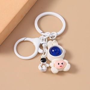 Cute white astronaut keychain with blue helmet and mini figure on beige background