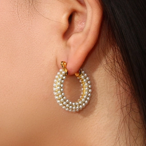 Detail of 18K gold plated hoop earrings with rows of elegant white pearls on model ear