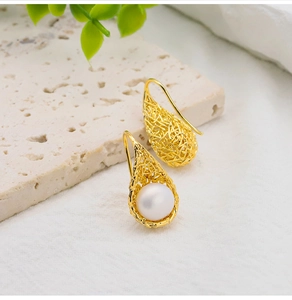 Macro shot of 18k gold bird nest drop earrings with white freshwater pearls on stone