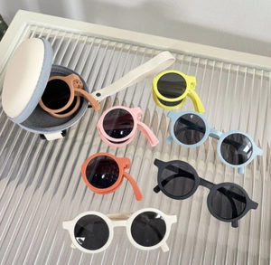 Foldable kids sunglasses in macaron colors with a portable round storage case and hand strap
