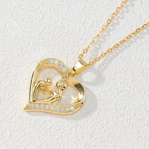 Macro shot of 18k gold heart necklace featuring mother and child embrace with zircons