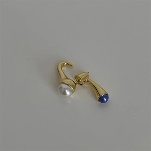 Detalle de pendientes bañados en oro con perla blanca y piedra natural azul engastada